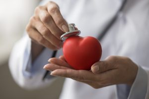 Hands,Of,Female,Cardiologist,Applying,Stethoscope,To,Red,Heart,Shaped