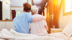 Nurse,In,Hospice,Hugs,Elderly,Woman,On,Bed,For,Comfort