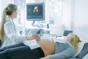 In the Hospital, Pregnant Woman Getting Ultrasound Screening, Obstetrician Checks Picture of the Healthy Baby on the Computer Screen. Happy Future Mother Waiting for her Baby to Born.