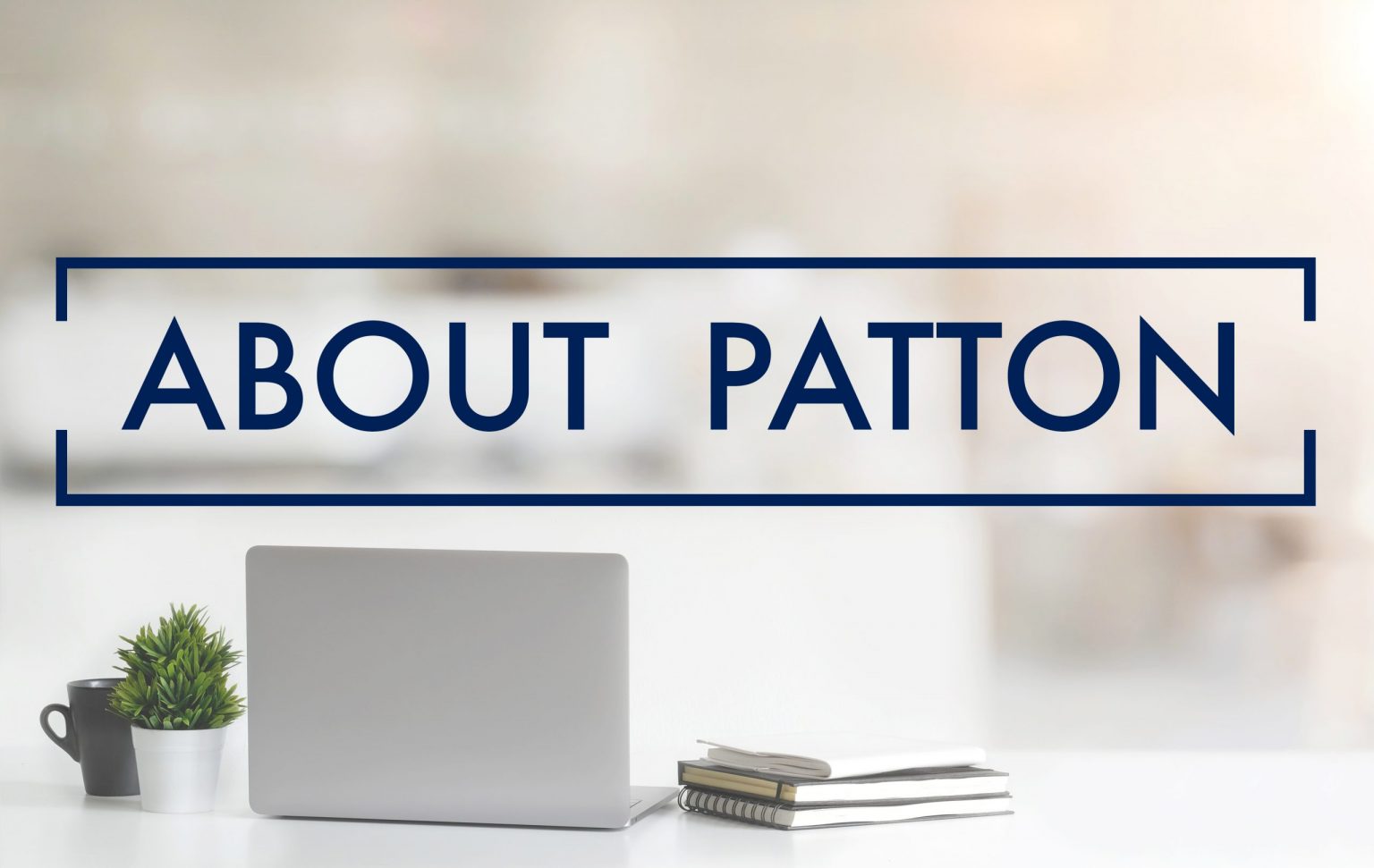 Close up view of simple workspace with laptop, notebooks, coffee cup and tree pot on white table with blurred office room background with the words "About Patton" in the foreground"
