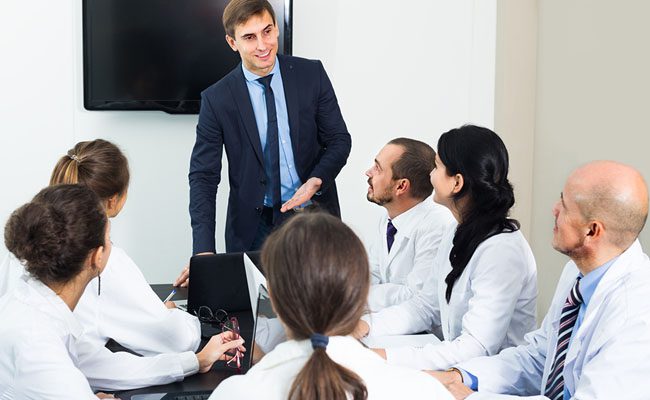 Multinational interns and happy professor cooperating at hospital meeting