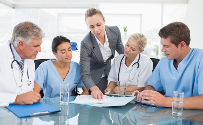 Successful medical doctors are making notes and smiling while sitting at the conference