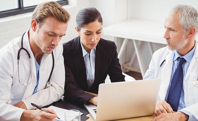 Medical team using laptop in conference room in hospital