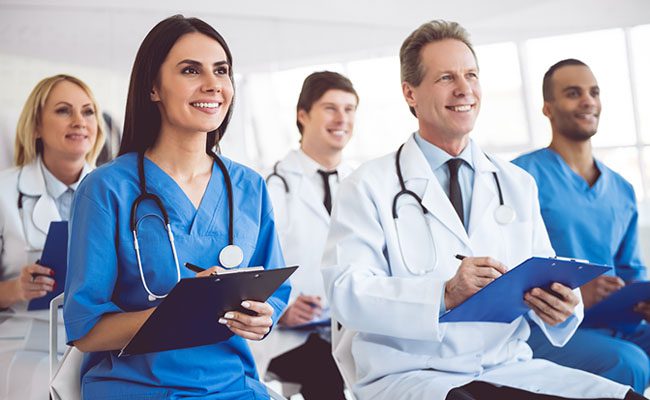 Successful medical doctors are making notes and smiling while sitting at the conference