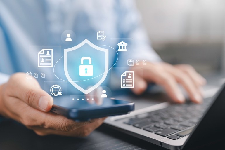 Digital cybersecurity shield displayed over a laptop and phone