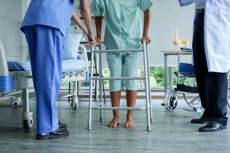 Patient using a walker with healthcare staff nearby