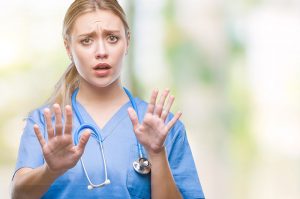 Young blonde surgeon doctor woman over isolated background afraid and terrified with fear expression stop gesture with hands, shouting in shock. 