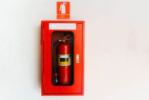 Fire Extinguisher in red cabinet on white wall at exterior buildings.