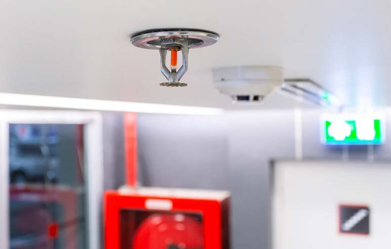 Fire sprinkler, alarm, and exit sign in a facility