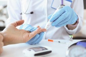 Doctor with gloves piercing patients finger with lancet closeup. Blood glucose monitoring concept