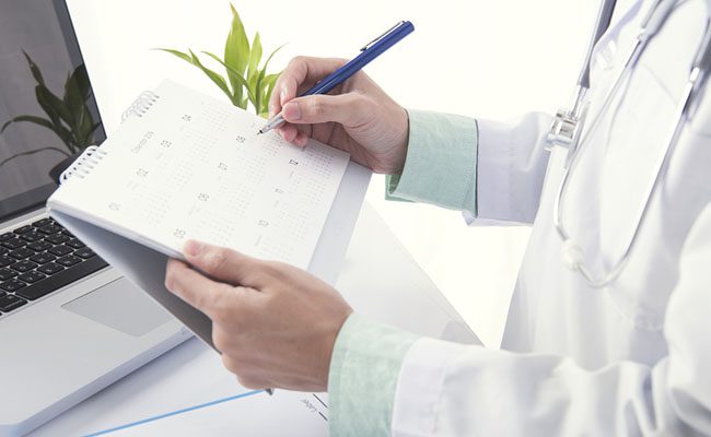 Doctor hand marked appointment for patient on calendar. concept planner health care.