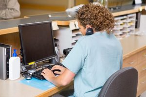 Rear,View,Of,Female,Nurse,Answering,Telephone,While,Working,On