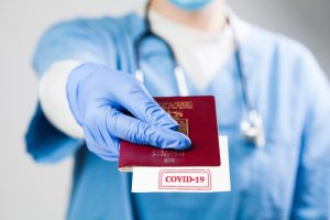 Nhs,Doctor,Holding,Passport,With,Covid-19,Sign,Stamped,Onto,White