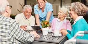 Caregiver with tablet pc and a group of seniors in retirement home