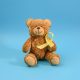 brown teddy bear holds in his paw a yellow ribbon folded in a loop on a blue background