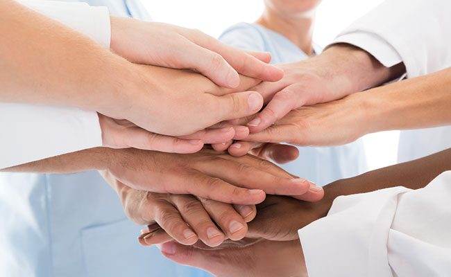 Cropped image of medical team stacking hands against white background