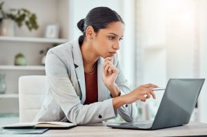 woman at her desk pointing at laptop screen